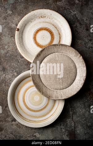 Three different homemade ceramic plates on dark gray background, top view Stock Photo