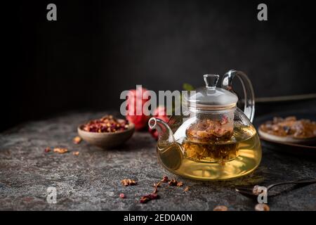 herbal flower tea from the petals of rose in a glass teapot on dark gray background Stock Photo