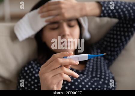 Focus on electronic thermometer in hand of sick asian woman Stock Photo