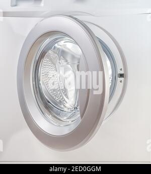 Open door of a washing machine close up with empty illuminated drum Stock Photo