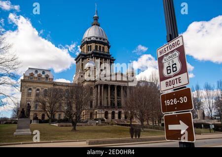 Springfield, IL—March 15, 2019; Route 66 road sign is displayed on light pole in front of the Illinois State Capital indicating historic location of t Stock Photo
