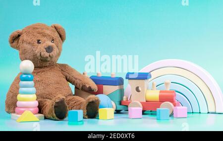 Kids toys collection. Teddy bear, wooden rainbow, train and baby toys on light blue background Stock Photo