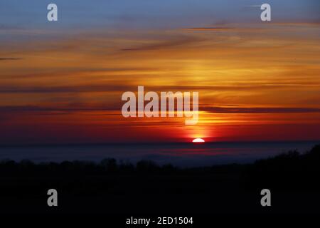 A rare phenomenon over the Baltic Sea where the sea is covered by a thin layer of clouds as seen here from Bornholm towards Sweden at sunset. Stock Photo