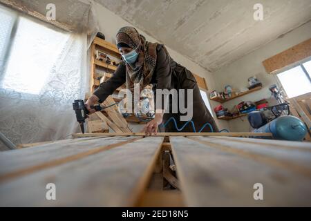 Bethlehem. 14th Feb, 2021. A Palestinian woman works at a carpentry shop in Al-Walajah village near the West Bank city of Bethlehem, on Feb. 14, 2021. Five years ago seven Palestinian housewives started their own project on wood recycling to make a living, turning waste timber into usable products, which were sold to souvenir shops and on social media. Credit: Luay Sababa/Xinhua/Alamy Live News Stock Photo