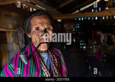 Chin woman with spiderweb tattoo smoking a pipe, Mindat, Chin state, Myanmar Stock Photo