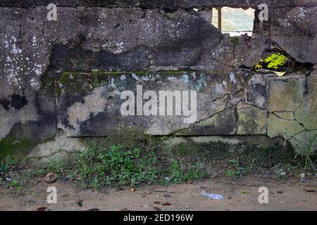 Blank stone plate on rustic old stone wall. Cracked concrete wall with empty name plate. Mossy stone mockup. Weathered concrete masonry detailed photo Stock Photo