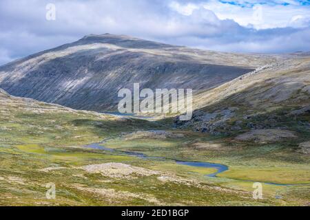 River in the tundra, barren landscape, behind mountain, Dovrefjell National Park, Oppdal, Norway Stock Photo