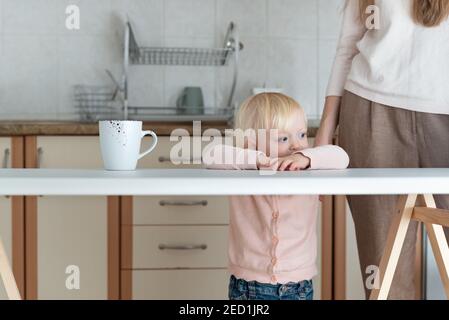Young mom and baby in the kitchen. Mother and baby morning Stock Photo