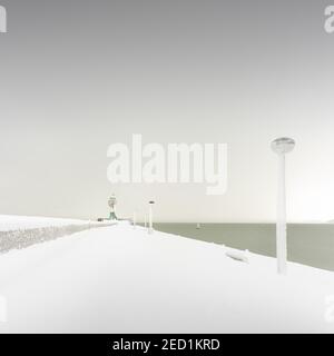 Iced quay wall and lighthouse in the harbour of Sassnitz on the island of Ruegen, Mecklenburg-Western Pomerania, Germany Stock Photo