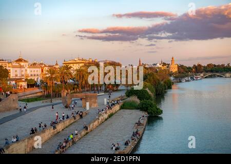 Waterfront promenade Muelle de la sal at the river Rio Guadalquivir with Monumento a la Tolerancia and Torre del Oro, sunset, Sevilla, Andalusia Stock Photo