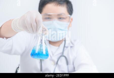 Young Scientists shaking blue liquid chemical in Erlenmeyer flask. Covid-19 testing in laboratory and Health care and medical concept. Stock Photo