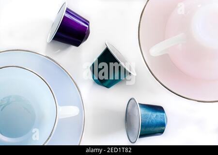 Top view of collection of coffee pods placed near empty ceramic mug and saucer on white background Stock Photo
