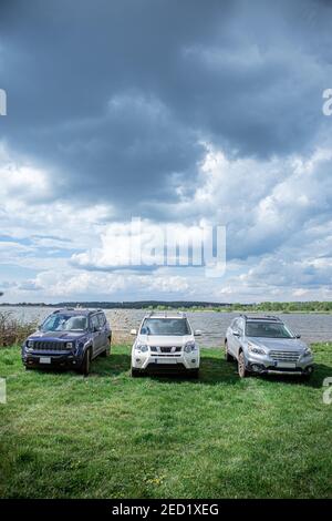 three off road suv cars standing at lake beach. copy space Stock Photo