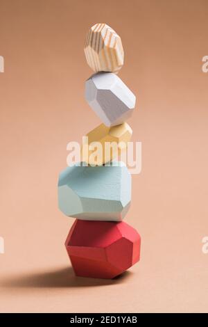 Wooden blocks in shapes of gems of various colors stacked on beige background in studio Stock Photo
