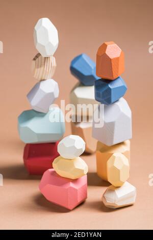 Wooden blocks in shapes of gems of various colors stacked on beige background in studio Stock Photo