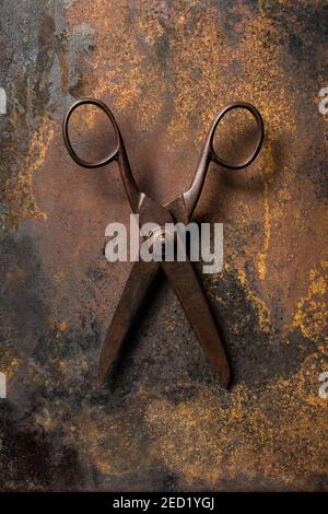 Top view of old metal scissors placed on dark table with rusty surface Stock Photo