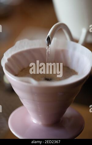 pouring water from kettle into glass pour over on scales closeup, blurred background, no people Stock Photo