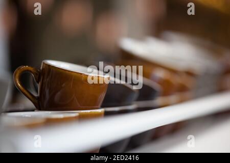 bunch of brown ceramic coffee cups on top of espresso machine, blurred background, horizontal, no people Stock Photo