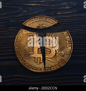 Broken bitcoin coin lies on a dark wooden background, close-up Stock Photo