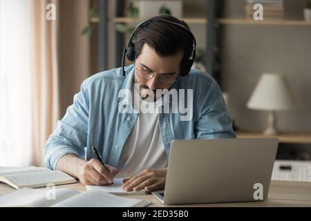 Millennial man focused on remote work make translation using laptop Stock Photo