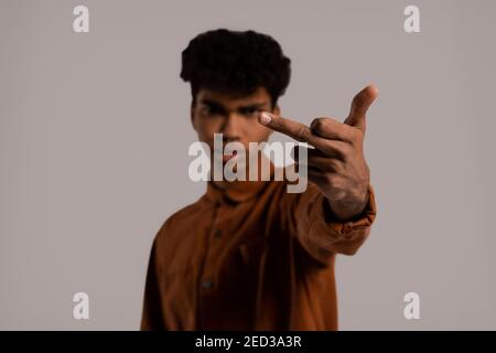 Close up photo of black man shows middle finger right in camera. Male wears shirt, isolated grey color background Stock Photo