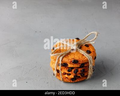 A stack of homemade oatmeal raisin cookies tied in string on a gray concrete surface. Copy space. Stock Photo