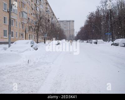 Moscow. Russia. February 13, 2021. Cars parked along the road on a winter day are covered in a thick layer of snow after a heavy snowfall. Stock Photo