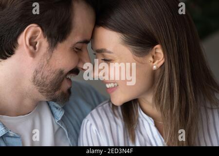 Young couple smiling leaning heads to one another whispering confessions Stock Photo