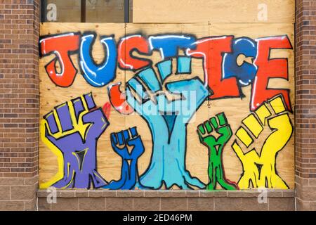 Painted mural with raised arms and clenched fists on boards covering store windows during the civil unrest after the killing of George Floyd in Minnea Stock Photo