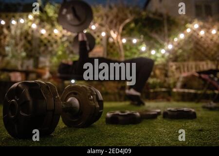 During lockdown in 2021, with gyms closed, a teenage boy trains in the garden in an improvided gym on a winter evening Stock Photo