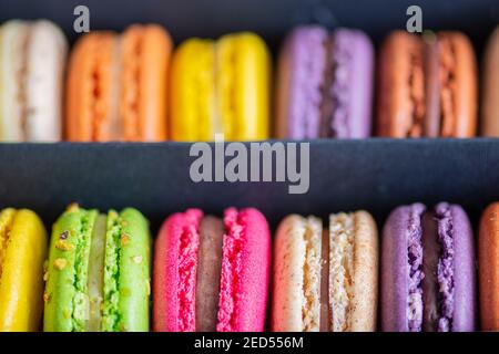 Various colorful macarons or French macaroons in a row in a gift box, sweet meringue-based confection made with egg white, icing sugar, granulated Stock Photo