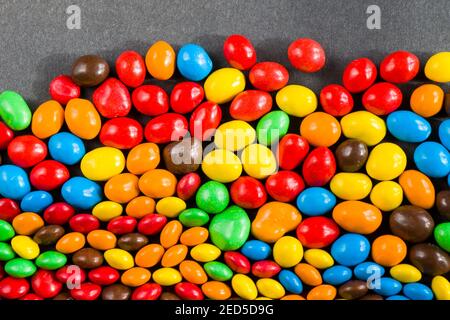 M&M's candy on the red background, colorful candy and multicolored