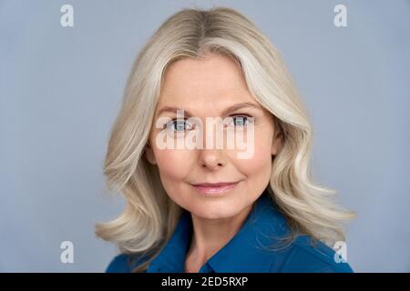 Confident mid aged business woman looking at camera isolated on grey, headshot. Stock Photo