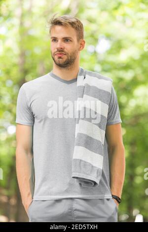 Taking minute break. Man athlete with towel after running outdoor, nature background. Athletic man relaxing break. Athlete with towel takes break during exhausting training. Runner workout outdoor. Stock Photo