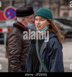 Prague, Czech Republic. 02-13-2021. Young woman and an old man walking in opposite direction in the city center of Prague during a cold winter day. Stock Photo