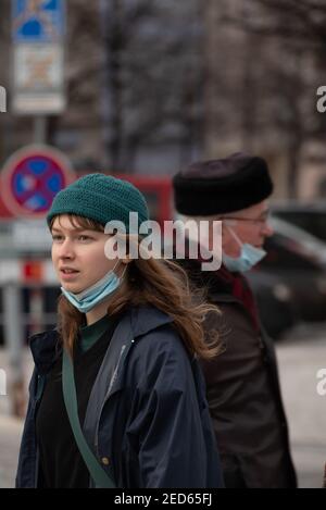 Prague, Czech Republic. 02-13-2021. Young woman and an old man walking in opposite direction in the city center of Prague during a cold winter day. Stock Photo