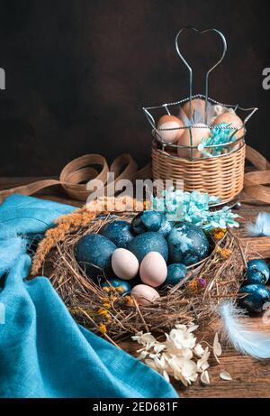 Chicken and quail eggs in a nest and in a basket on a brown background. Stock Photo
