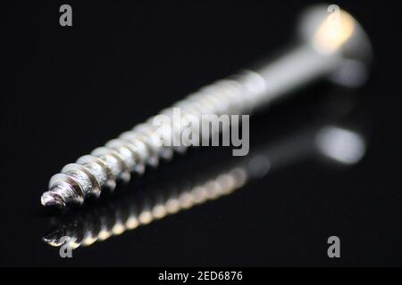 Macro Close up of a Steel Screw on Black Reflective Surface and Background Stock Photo