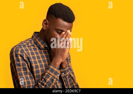 Upset black guy covering face with two hands in despair Stock Photo