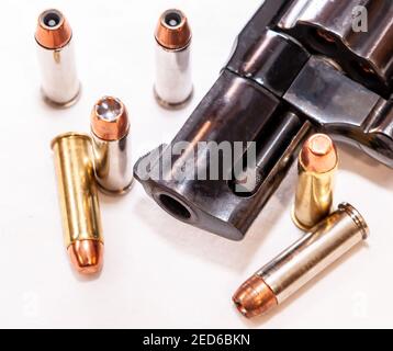 A black snub nosed 38 special  revolver muzzle with six bullets to it next to it on a white background Stock Photo