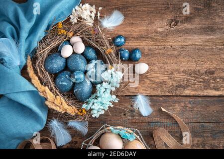 A beautiful Easter composition with colored eggs of different types in a bird's nest. Stock Photo