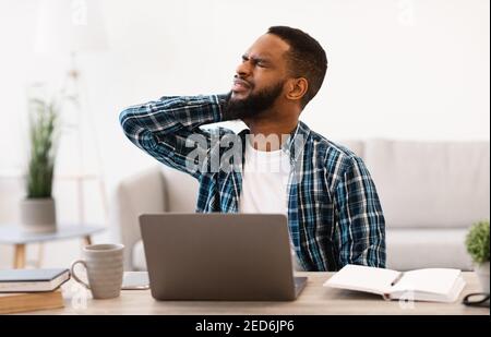 African Businessman Massaging Aching Neck Tired After Computer Work Indoor Stock Photo