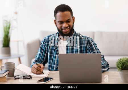 Black Business Guy Working At Laptop Taking Notes In Office Stock Photo