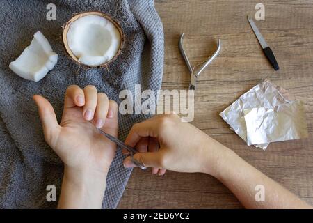 Hand care, folk hand care. Manicure with coconut oil, manicure tools: scissors, nail file. Foil Gel Polish Remover. Beauty and spa concept. Stock Photo