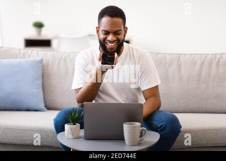 Black Man Using Voice Assistant Holding Cellphone Near Mouth Indoors Stock Photo