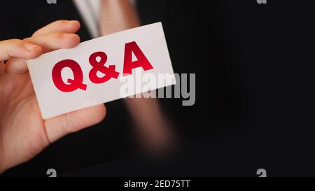 Q and A Questions and Answers sign on business card shown by a businessman,. Business concept. Stock Photo