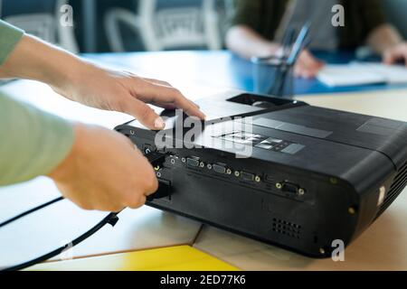 Hands of young businesswoman or coach switching on projector while going to make presentation for colleagues at business conference Stock Photo