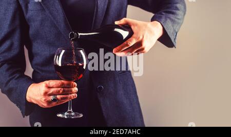 Waiter pouring red wine in a glass. Sommelier man, degustation, winery, male winemaker. Red wine is poured from bottle to glass Stock Photo