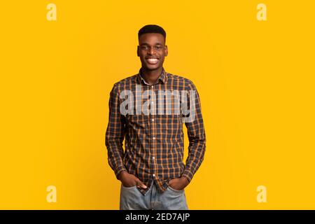 Portrait Of Young Handsome Black Guy In Checkered Shirt Over Yellow Background Stock Photo