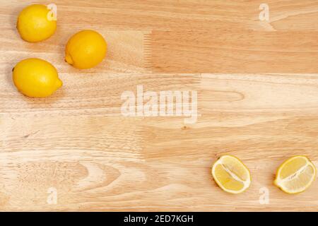 whole lemons and sliced lemons on wooden table, wooden bottom Stock Photo
